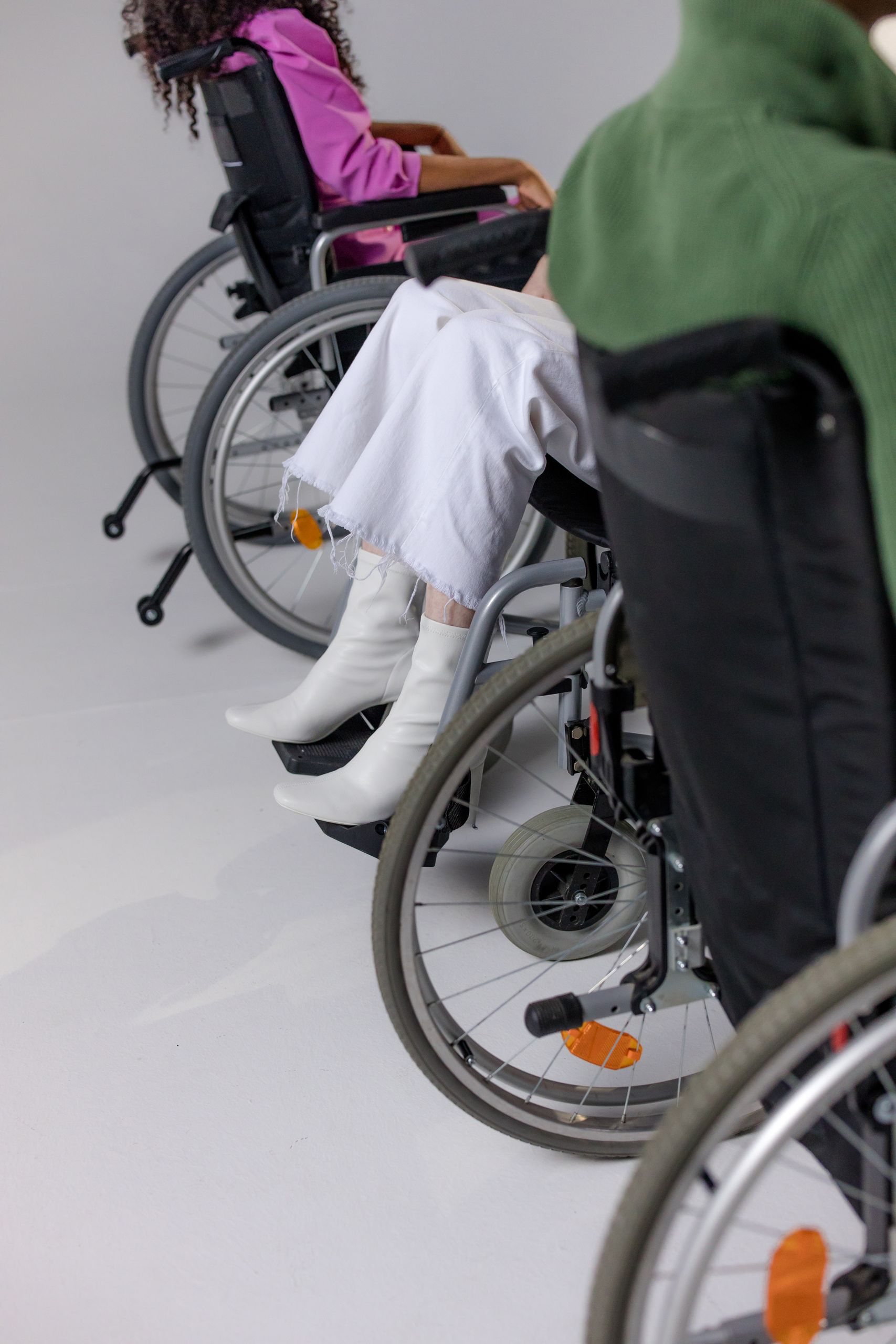 Stylish people in wheelchairs wearing trendy outfits for a modern fashion shoot.