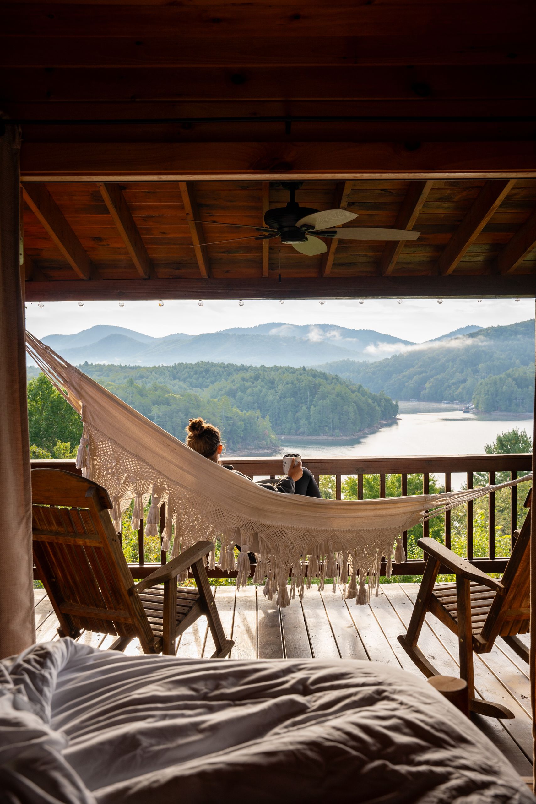 Relaxing on a porch with hammock facing a serene lake and mountain view.